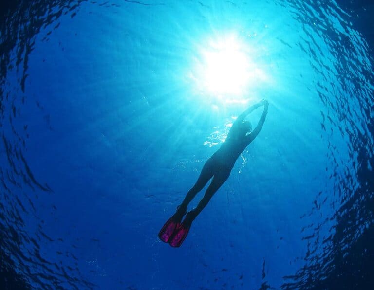 Silhouette of a person snorkeling in deep blue water